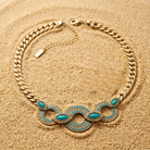 Gold necklace with turquoise stones on a sandy background