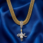 Gold chain necklace with crystals and a faux pearl pendant on blue satin fabric