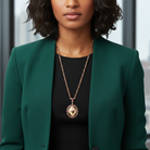 Woman wearing a green blazer and black top with a gold floral necklace.