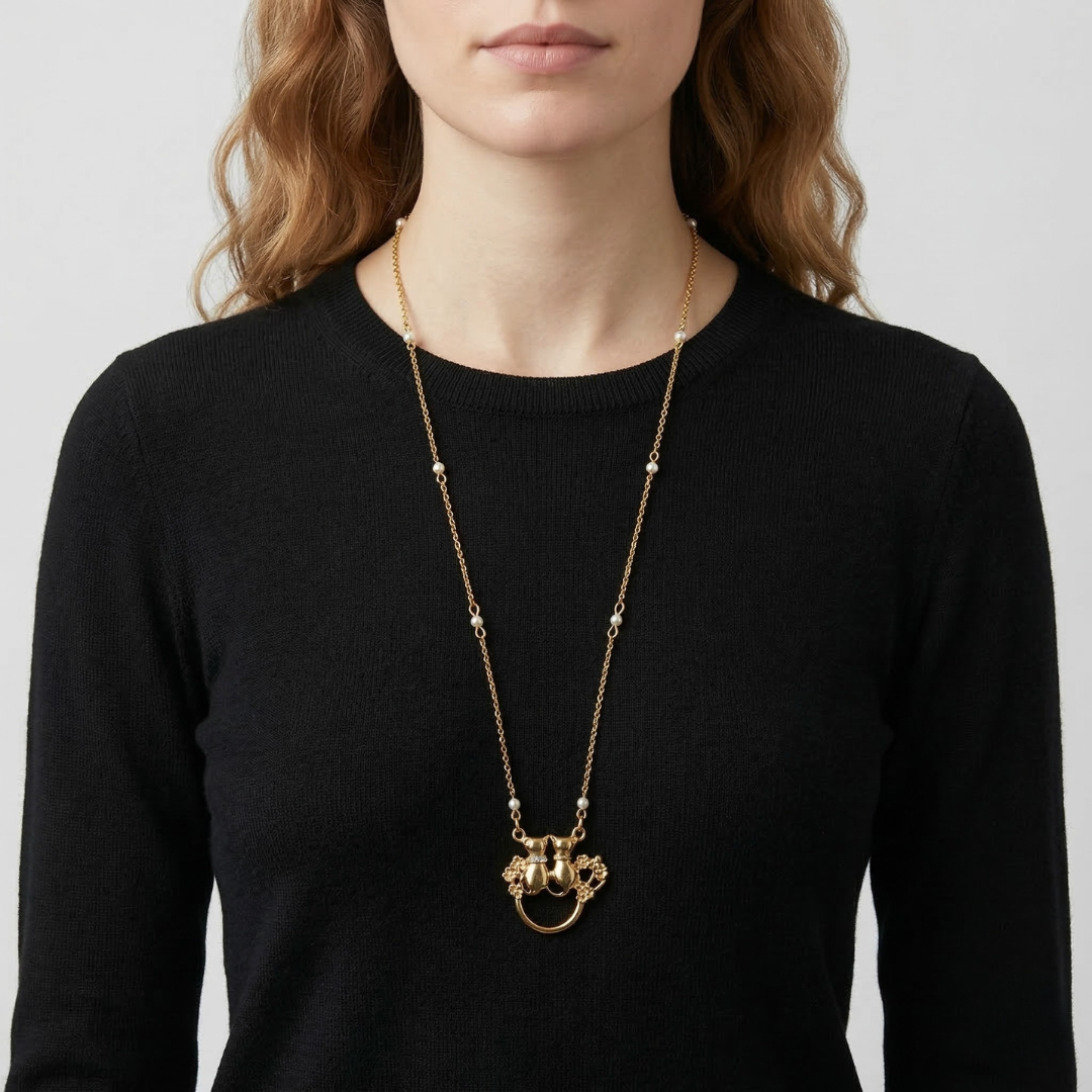 Woman wearing a gold necklace eye glass holder with a black top on a light gray background