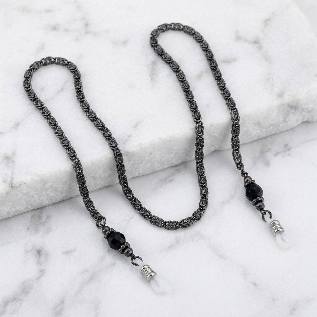 Black Chain And Black Eyeglass Holder Chain Necklace resting on white marble stone