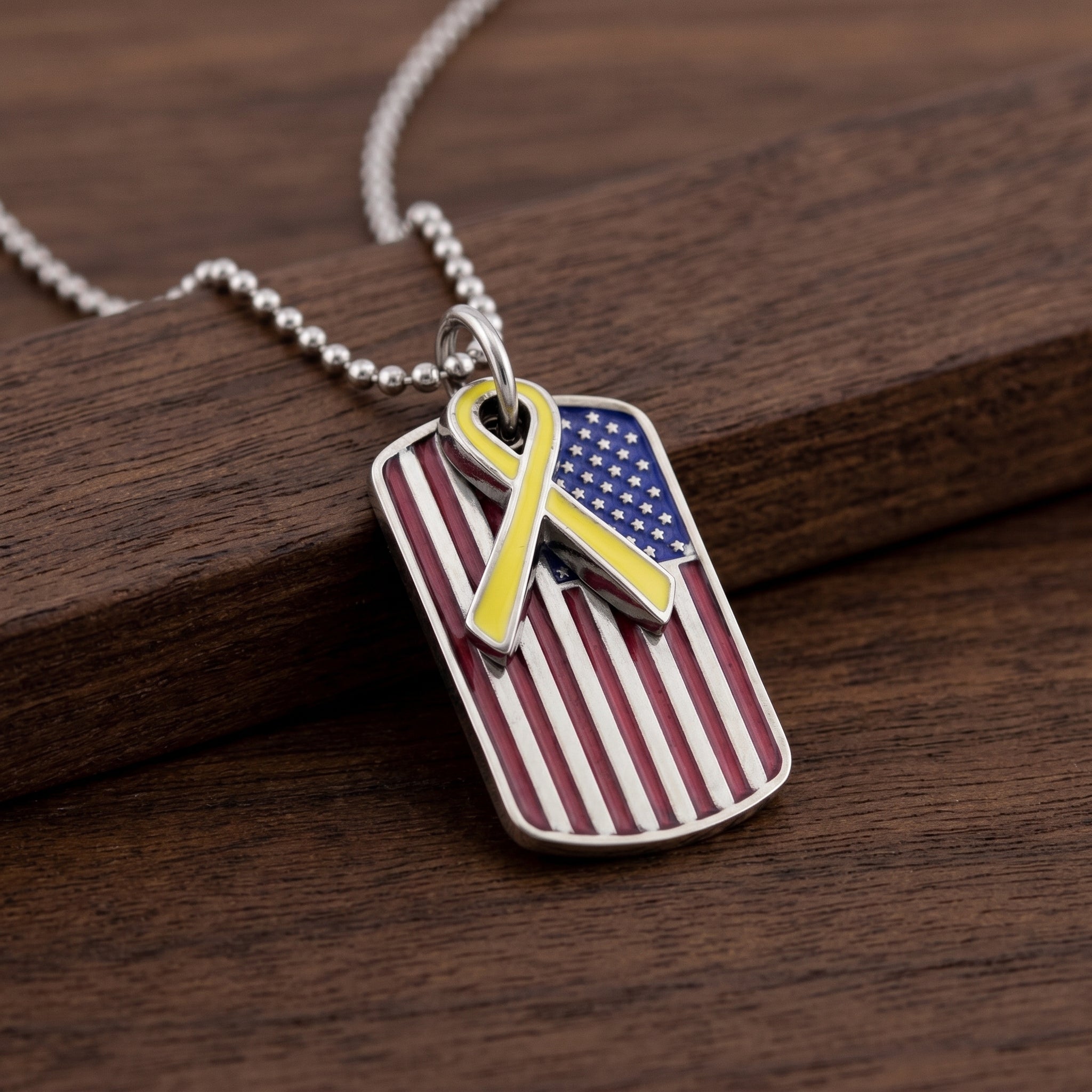 American flag dog tag pendant with yellow ribbon on a wooden surface