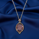 Gold necklace with a floral pendant on a blue fabric background