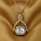 Gold necklace with a pendant featuring a large clear crystal on a gold fabric background