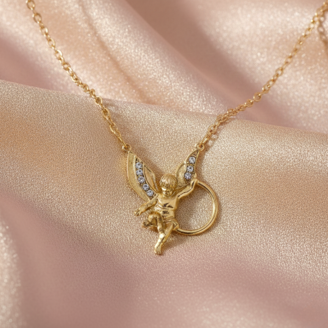 Gold necklace with a winged angel pendant on a pink fabric background