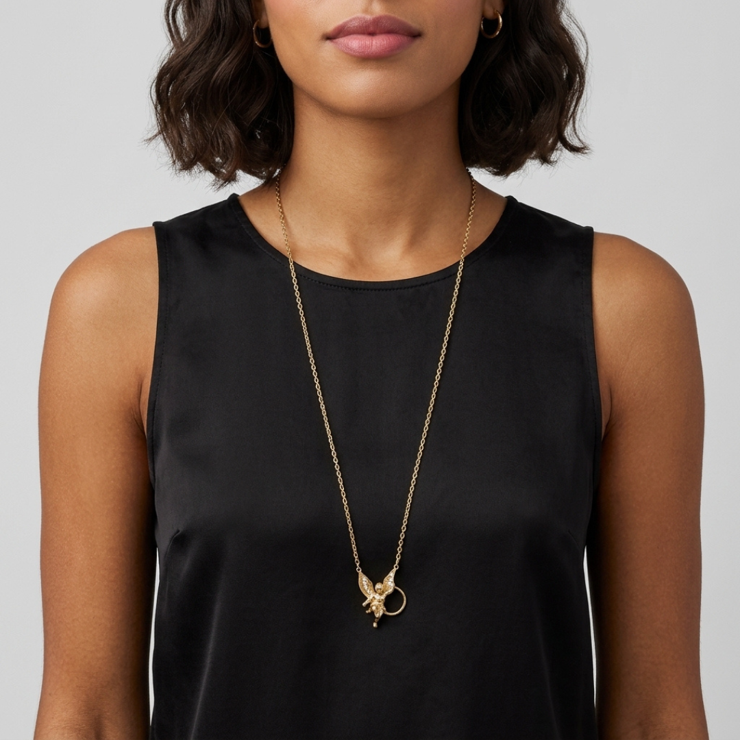 Woman wearing a black sleeveless top with a gold winged angel necklace.