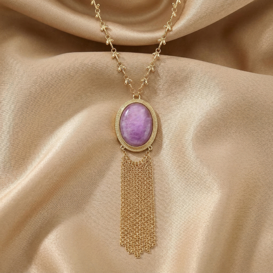 Gold necklace with a purple gemstone pendant on a beige fabric background