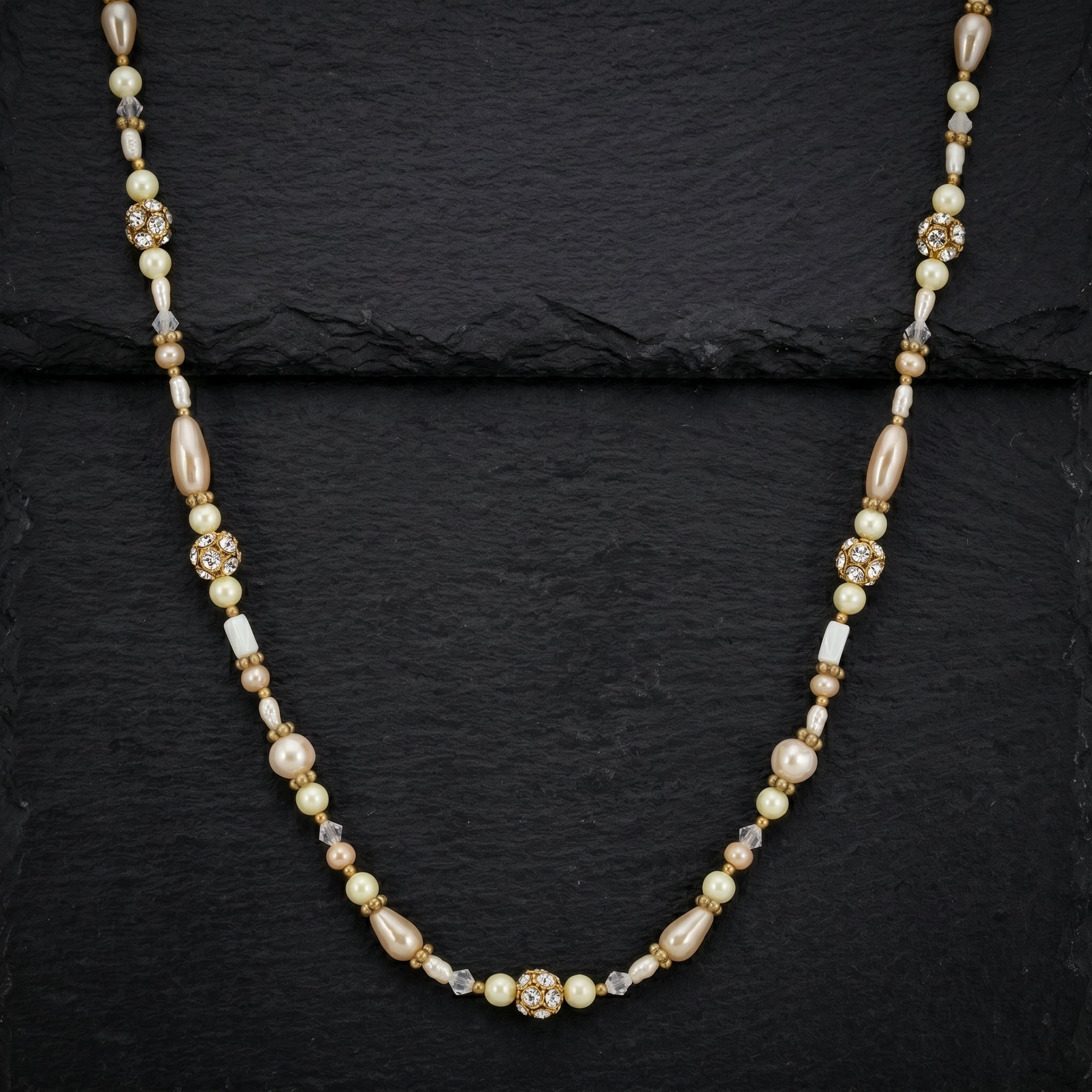 Antiquities Couture Faux Pearl And Crystal Rope Necklace resting on black stone