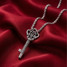 Silver key-shaped whistle pendant on a chain against a red fabric background
