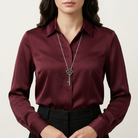 Person wearing a burgundy shirt with a silver key whistle necklace on a neutral background