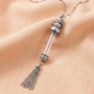 Antiqued Wing Cherub Angel Clear Crystal Glass Vial Tassel Necklace on peach colored linen