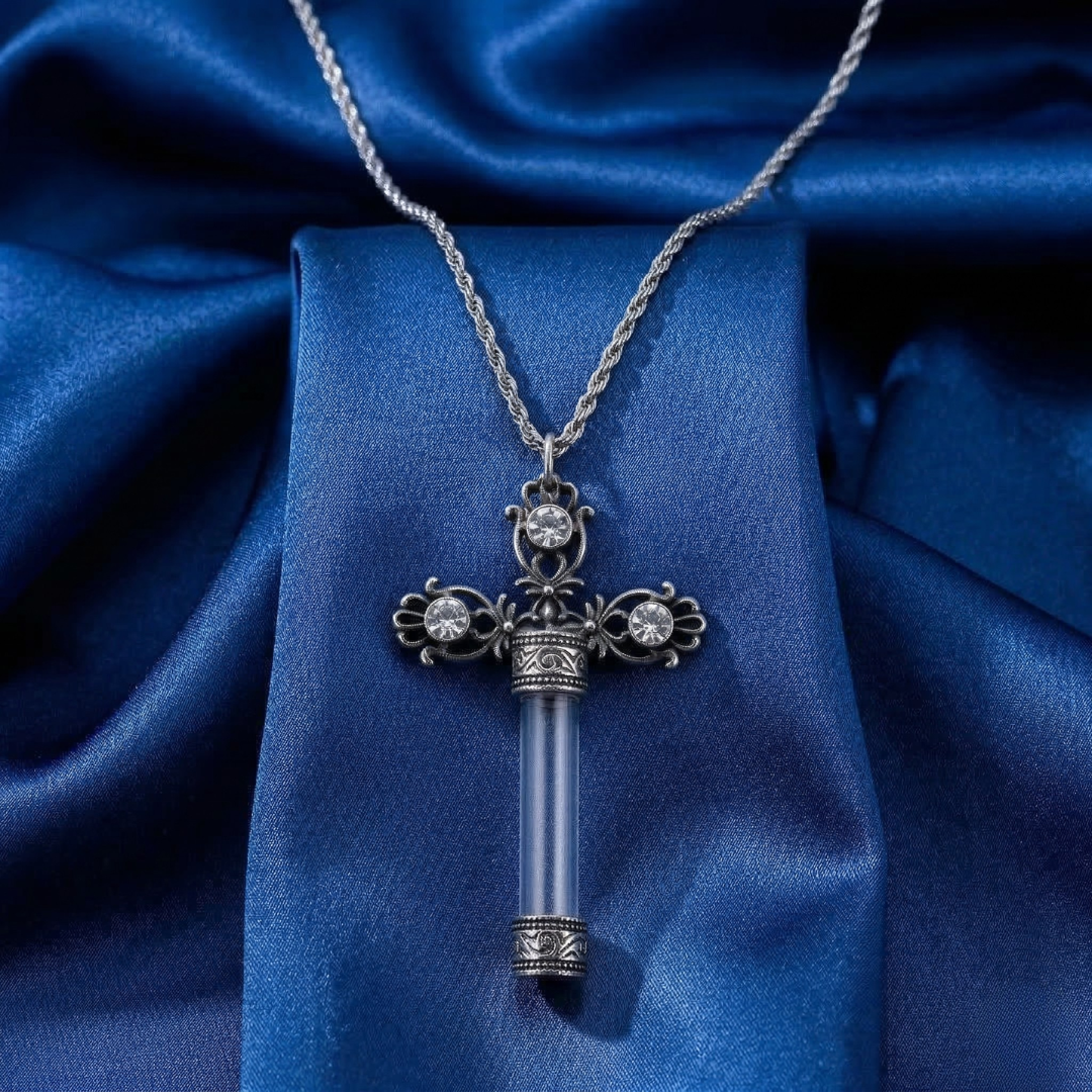 Decorative necklace with a glass cross vial pendant on a blue fabric background