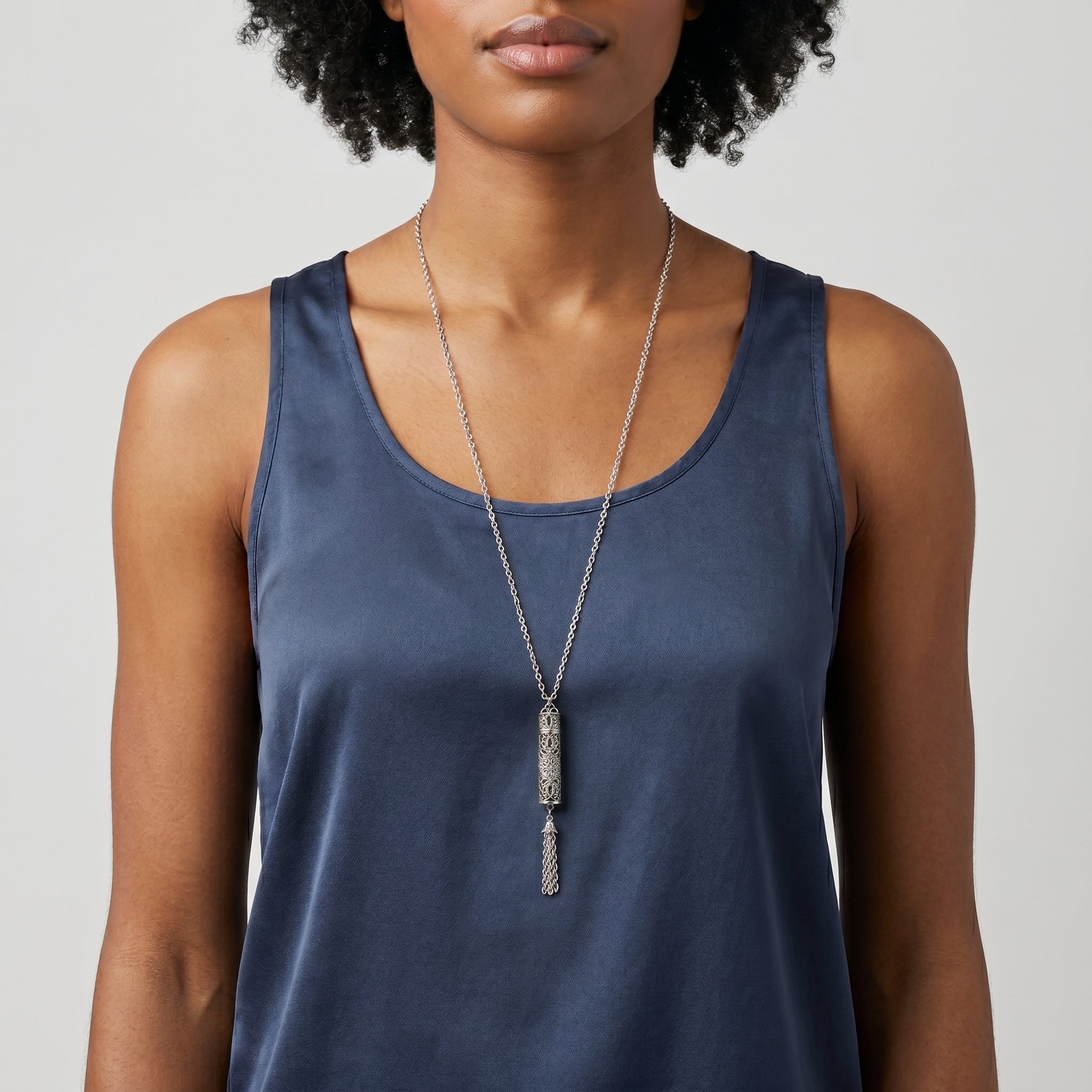 Woman wearing a blue tank top and a silver tone Antiqued Filigrana Glass Vial Tassel Necklace