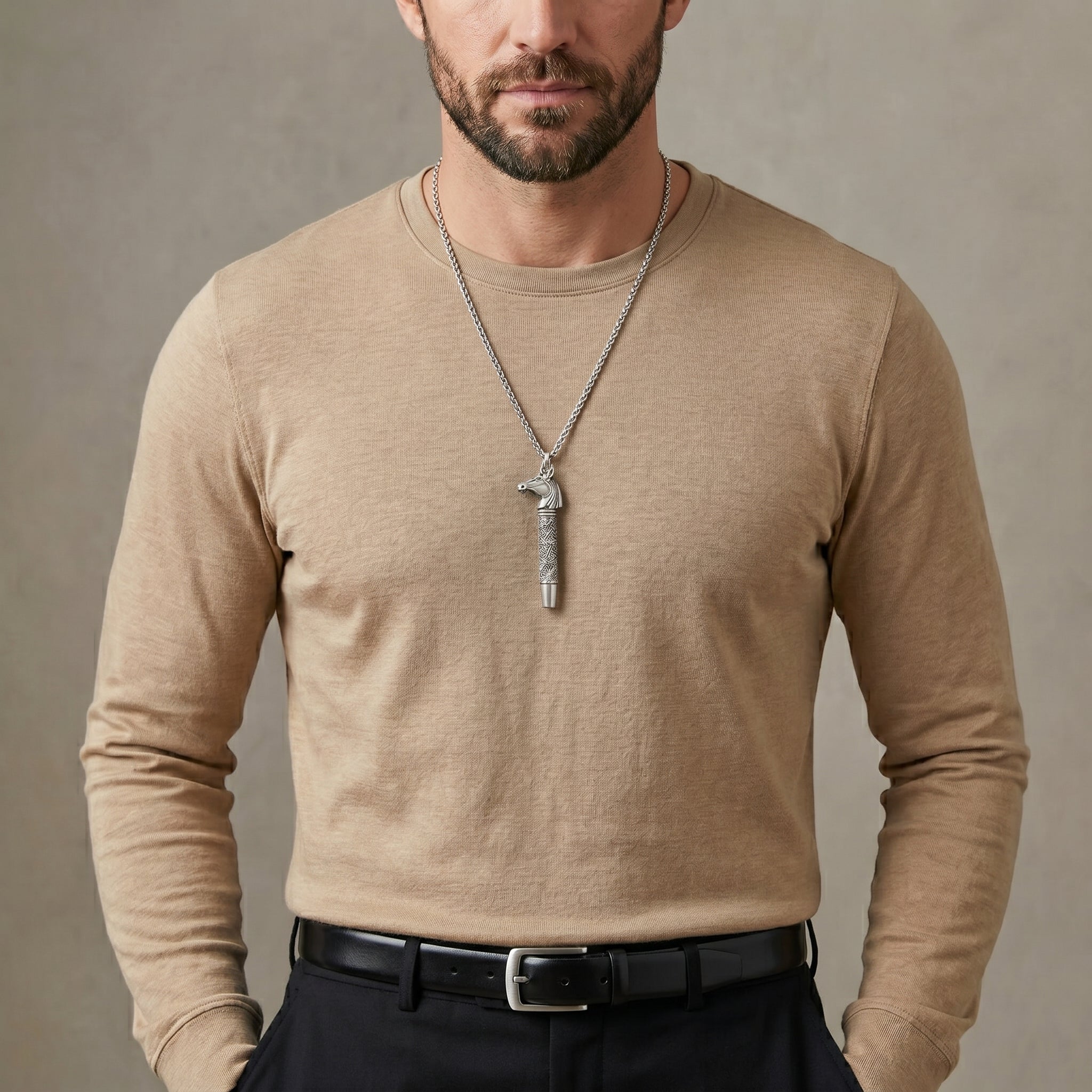 Man wearing a beige long-sleeve shirt with a horse whistle pendant necklace against a neutral background
