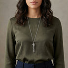 Silver tone Horse Head Whistle Necklace worn by a woman with a long sleeve dark green shirt. 