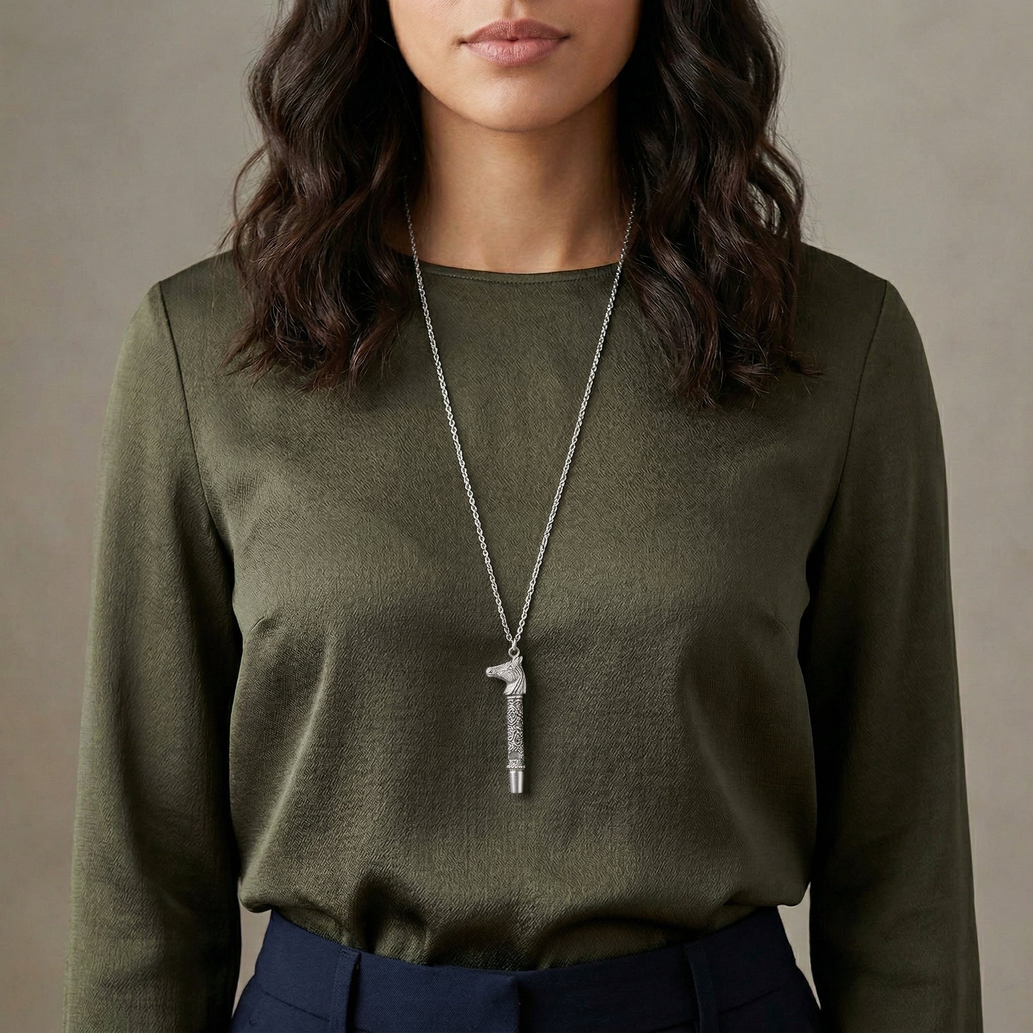 Silver tone Horse Head Whistle Necklace worn by a woman with a long sleeve dark green shirt. 