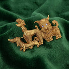 Gold dog-shaped brooches on a green fabric background