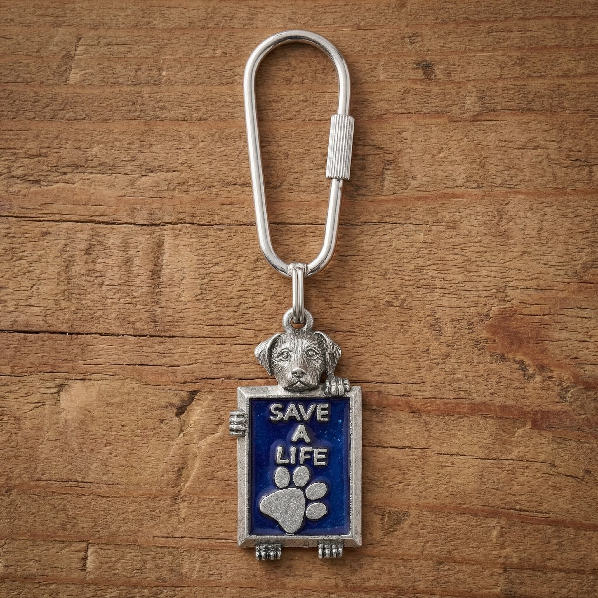Silver tone dog "Save A Life" keychain against a wooden surface