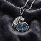Whimsical Cat & Blue Fish Pendant Necklace on a dark fabric background