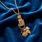 Gold tone cat pendant necklace with several charms on a blue fabric background