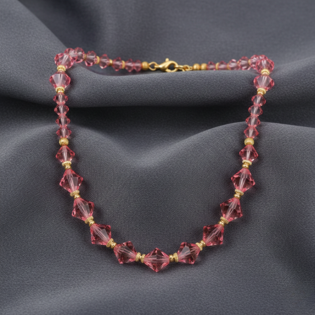 Beaded necklace with pink and gold beads on a dark fabric background