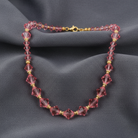 Beaded necklace with pink and gold beads on a dark fabric background