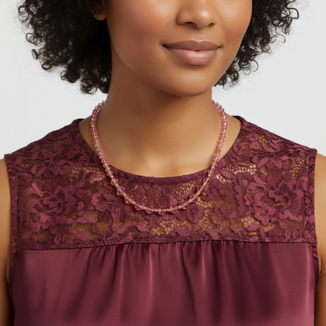 Woman wearing a burgundy lace top with a pink beaded necklace on a white background