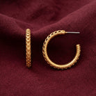 Gold Perforated Hoop Post Earrings displayed on a draped burgundy fabric background.