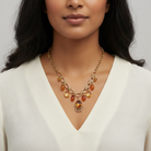 Woman wearing a gold necklace with amber-colored beads against a neutral background
