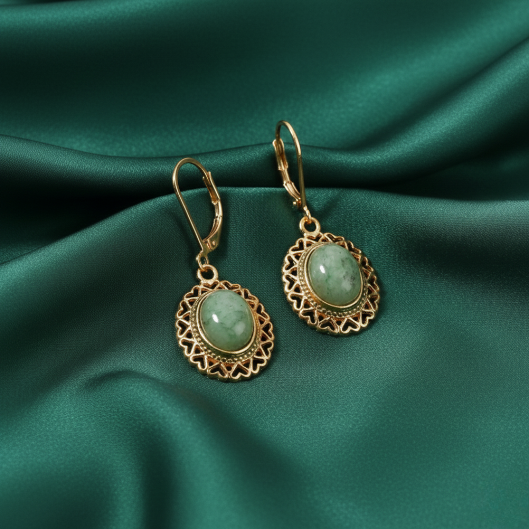 Gold earrings with green gemstones on a green satin background