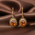 Gold earrings with Topaz stones on a brown fabric background