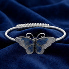 Silver tone Butterfly's Dance Blue Enamel Spring Hinge Bracelet resting on dark blue fabric