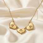 Gold necklace with heart-shaped pendants on a beige fabric background