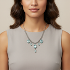 Woman wearing a necklace with light blue crystals against a neutral background