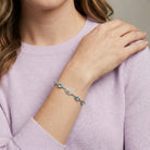 Person wearing a bracelet with blue crystals on a light purple sweater