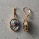 Mixed Flower Bouquet German Enameled Glass Drop Earrings on a gray cement surface