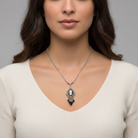 Woman wearing a silver necklace with a pendant against a neutral background