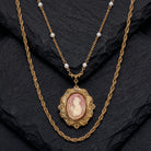 Gold necklace with a cameo pendant on a dark stone surface