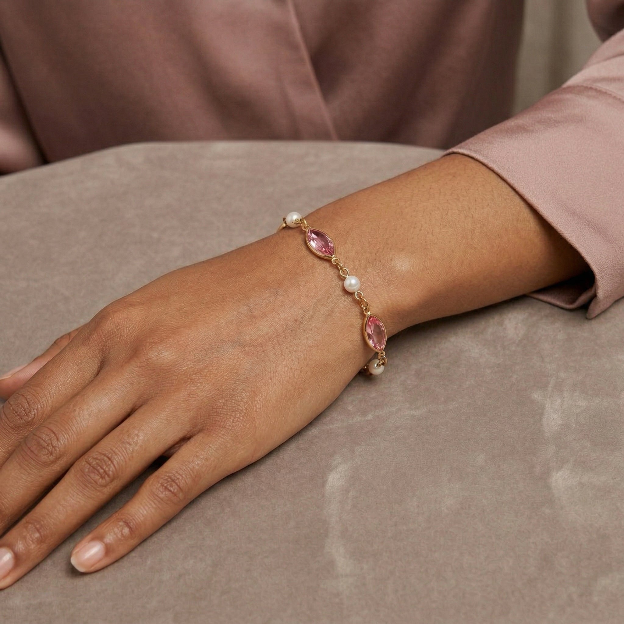 Woman in a soft pink shirt wearing a Navette Rose Pink Austrian Crystal & Faux Pearl Link Bracelet on her wrist