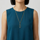 Woman in a blue top wearing a gold tone Crystal Tweezer Pendant Necklace