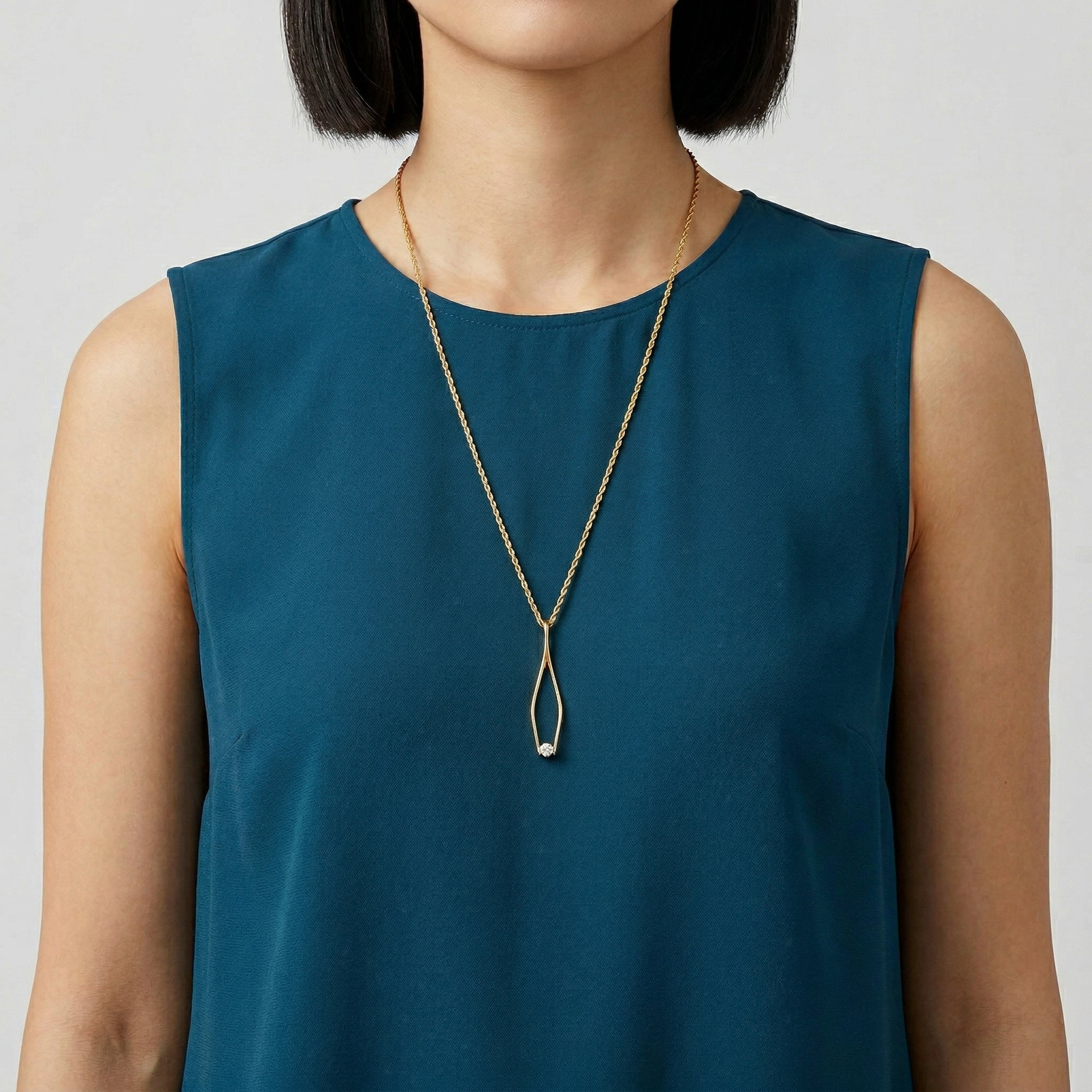 Woman in a blue top wearing a gold tone Crystal Tweezer Pendant Necklace