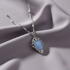 Necklace with a blue pendant on a soft pink fabric background