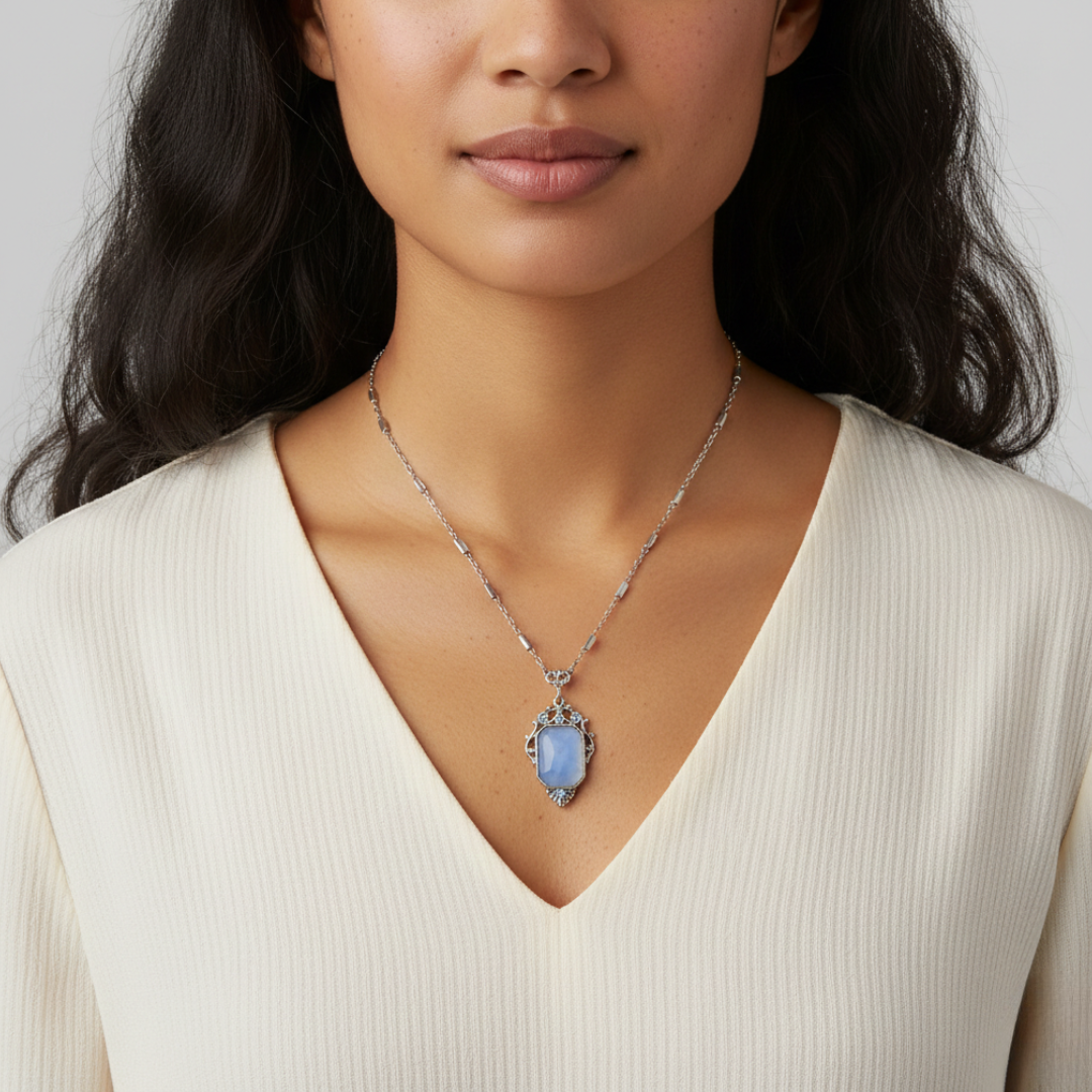 Woman wearing a necklace with a blue pendant against a neutral background