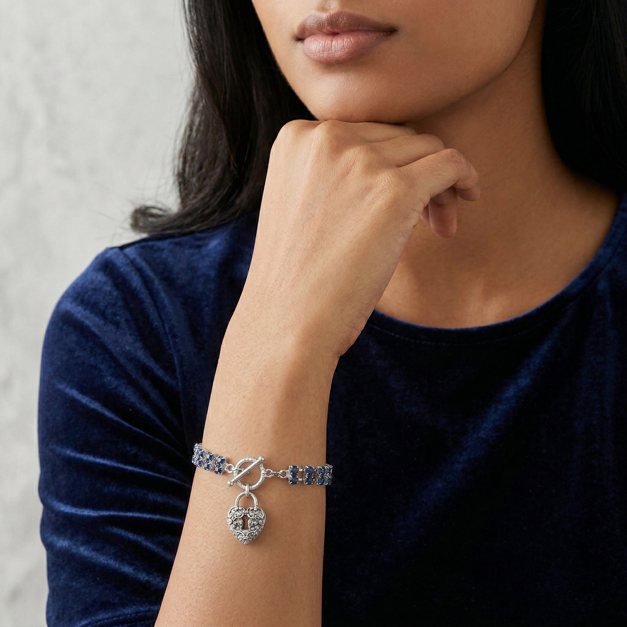 Woman in a dark blue top posing a Montana Blue Rhinestone Crystal Skeleton Keyhole Heart Charm Toggle Bracelet on her wrist