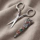 Opened Seamstress Essentials Scissors and cover resting on gray linen fabric 