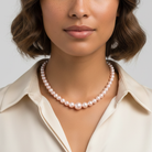 Woman wearing a Rosabella Pink faux pearl necklace against a neutral background