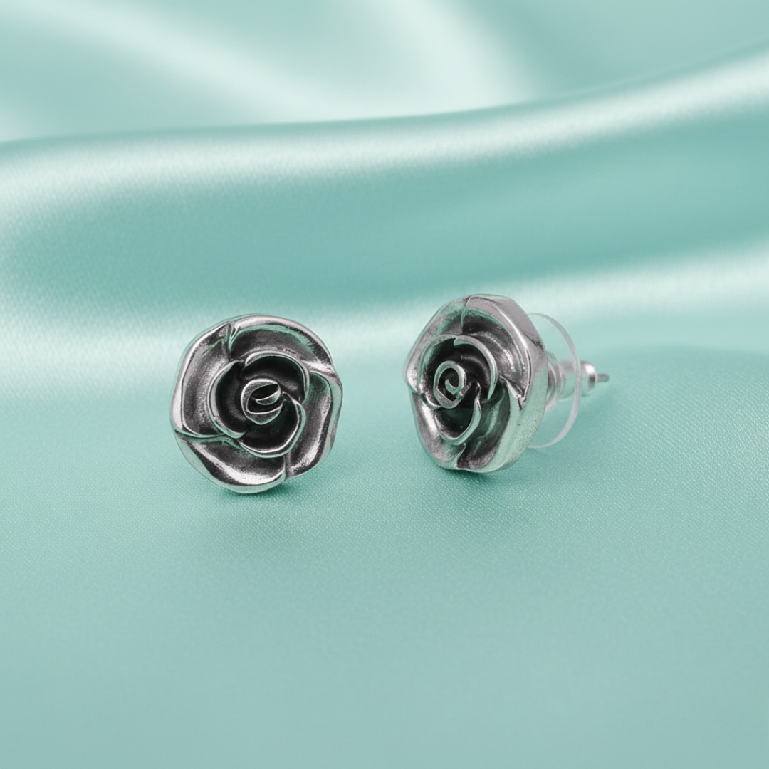 Silver rose-shaped pushback earrings on a light blue satin background