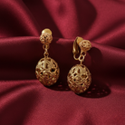Gold earrings on a red satin background