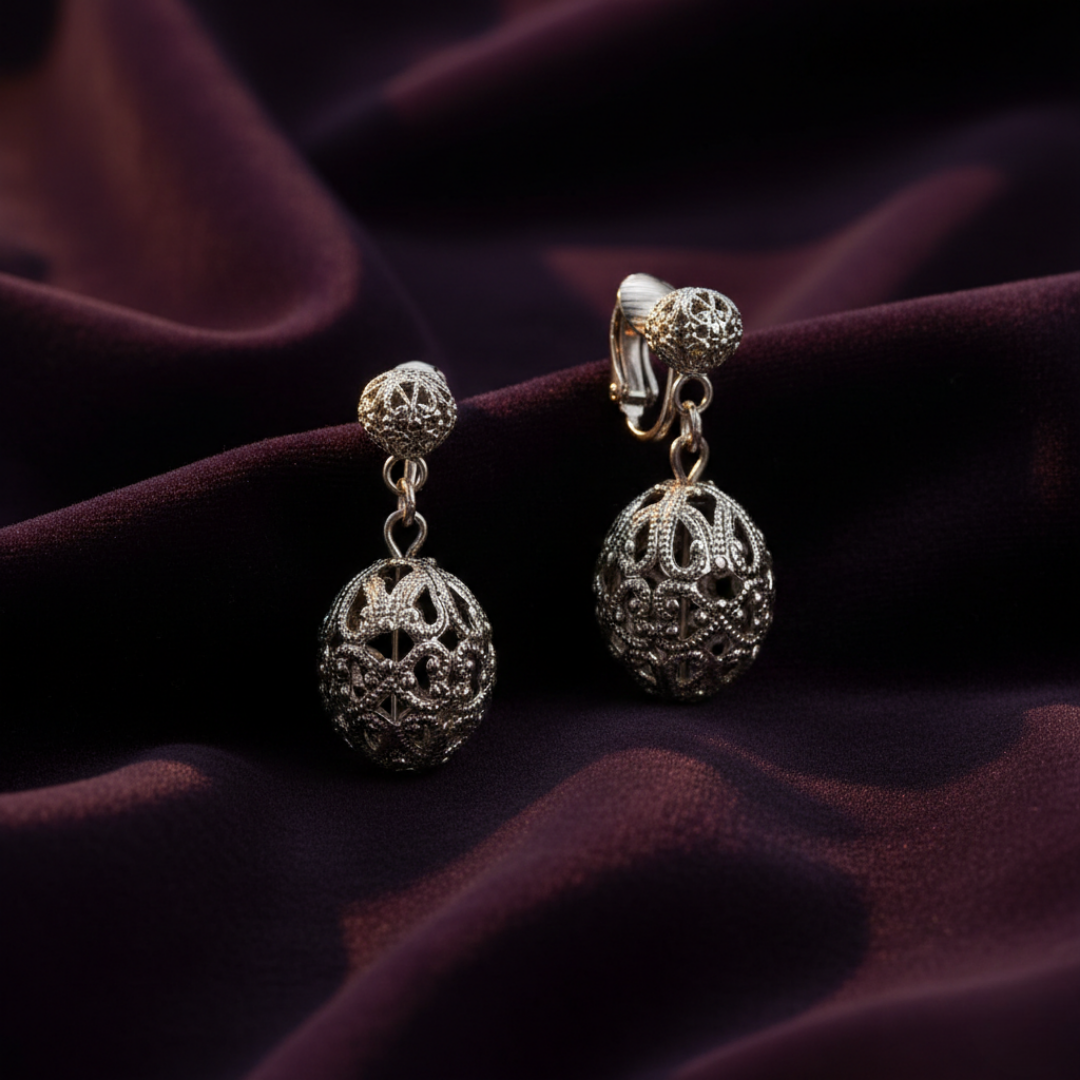 Pair of silver earrings on a dark purple fabric background