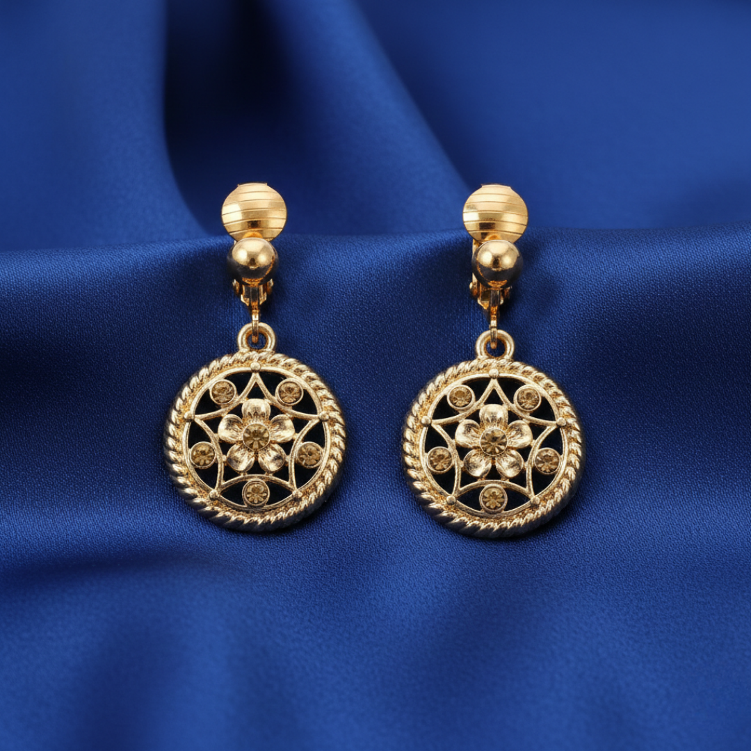 Gold earrings with intricate designs on a blue fabric background